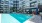 swimming pool in a courtyard with tables and lounge chairs
